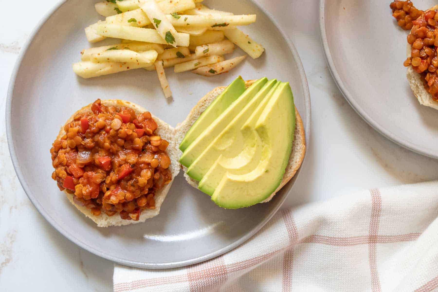Two plates with lentils and avocado on them.