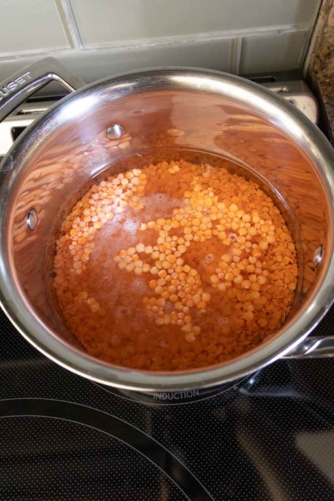 A pot of cooked lentils on a stove top.