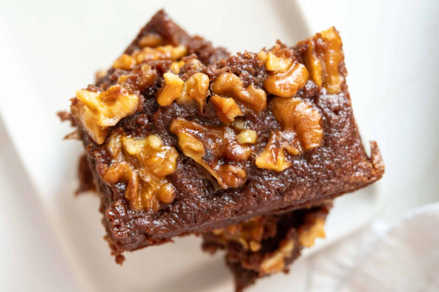 A stack of brownies with walnuts on a white plate.