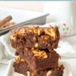 A stack of walnut brownies on a plate.