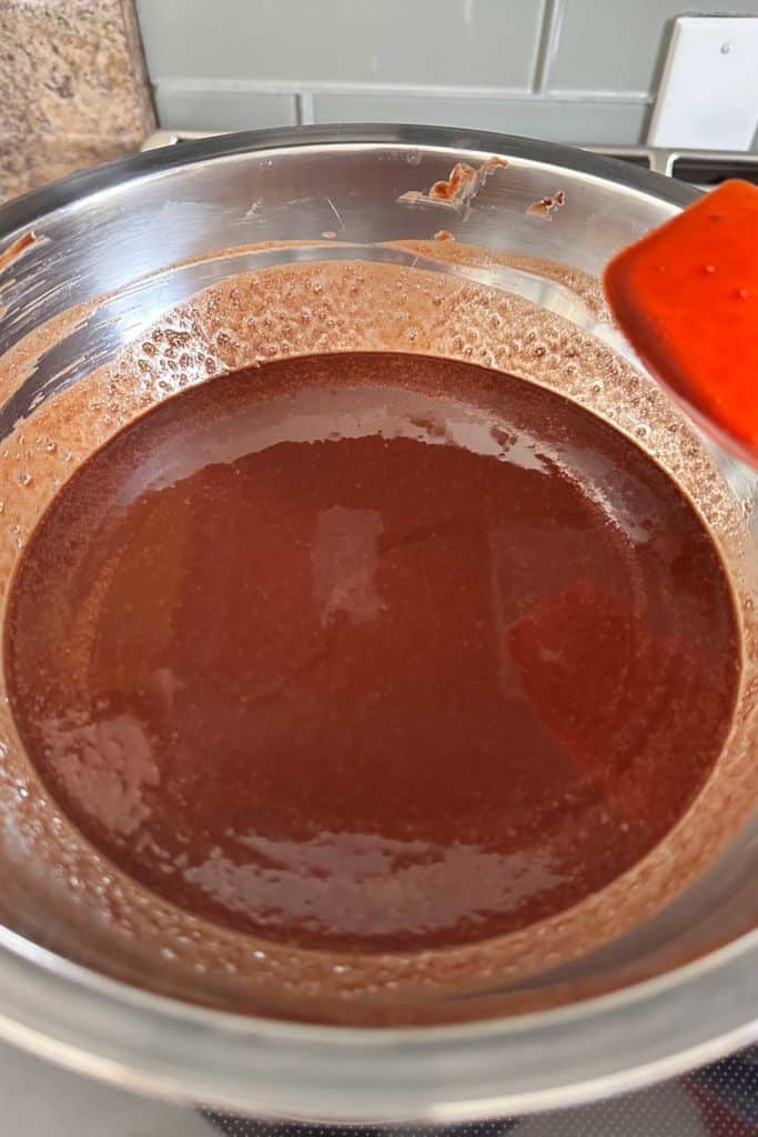 A bowl of chocolate is being stirred with a spatula.