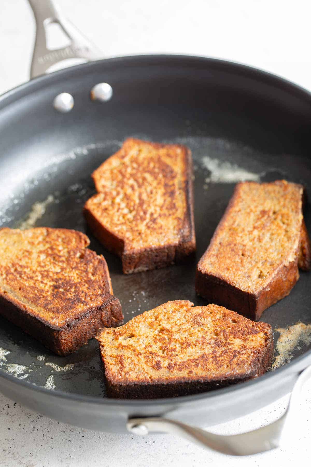 French toast being fried in a skillet.