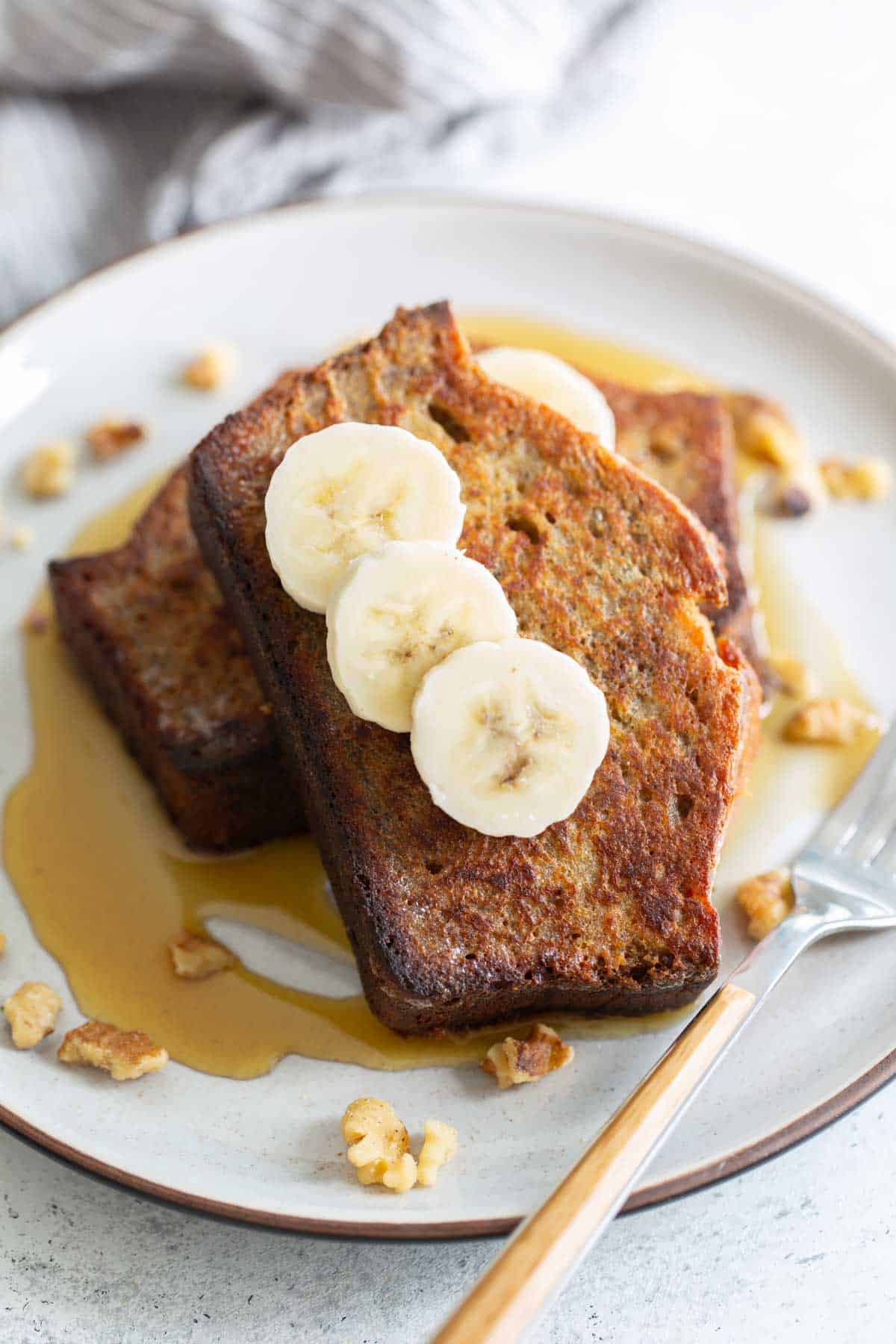 French toast with bananas and walnuts on a plate.