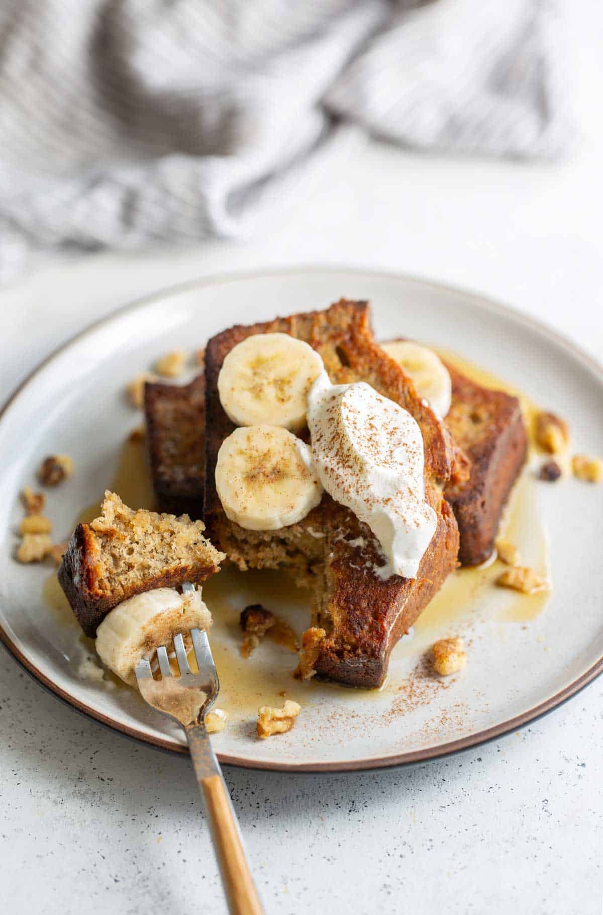 Banana french toast with whipped cream and bananas on a plate.