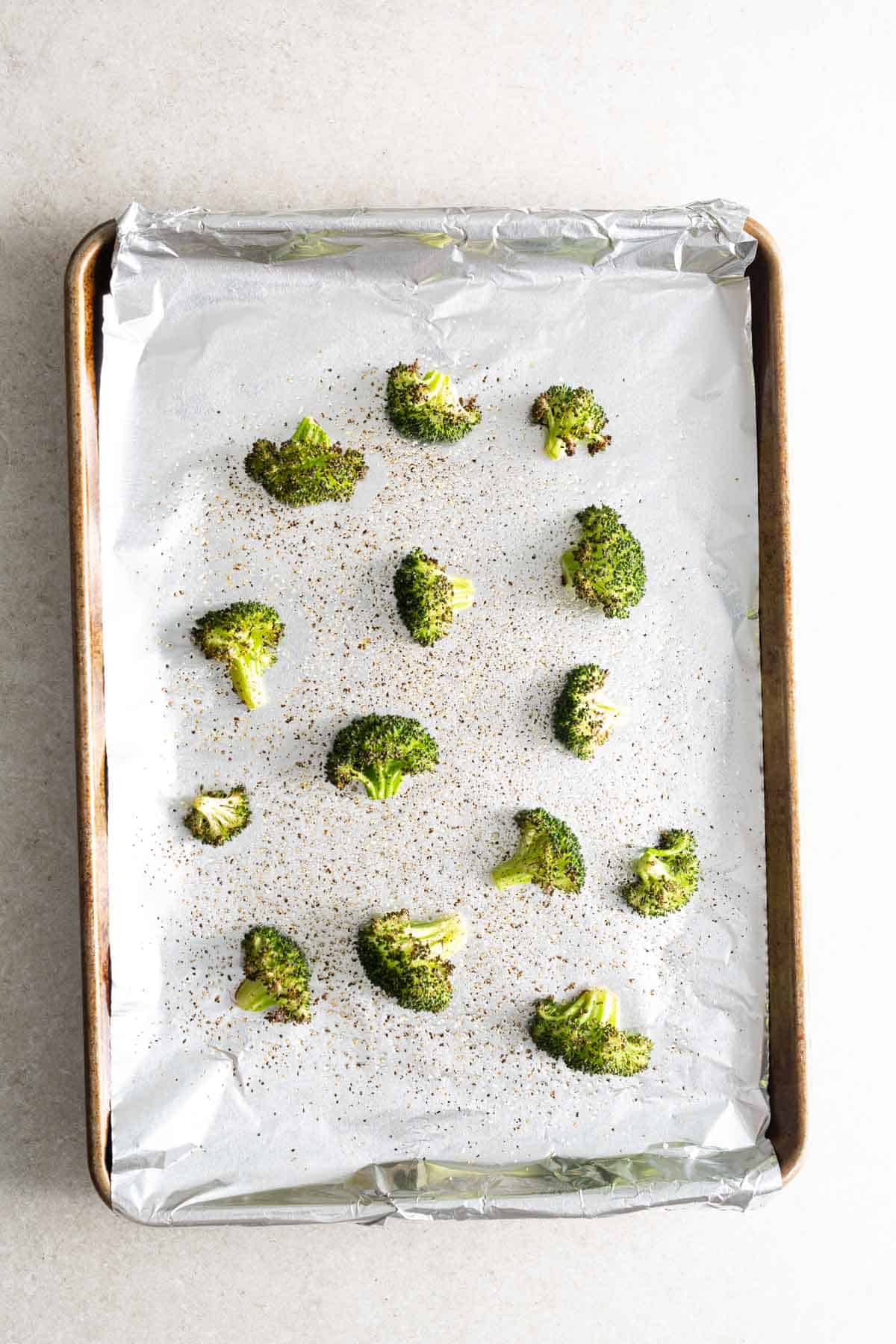 A baking sheet with broccoli on it.
