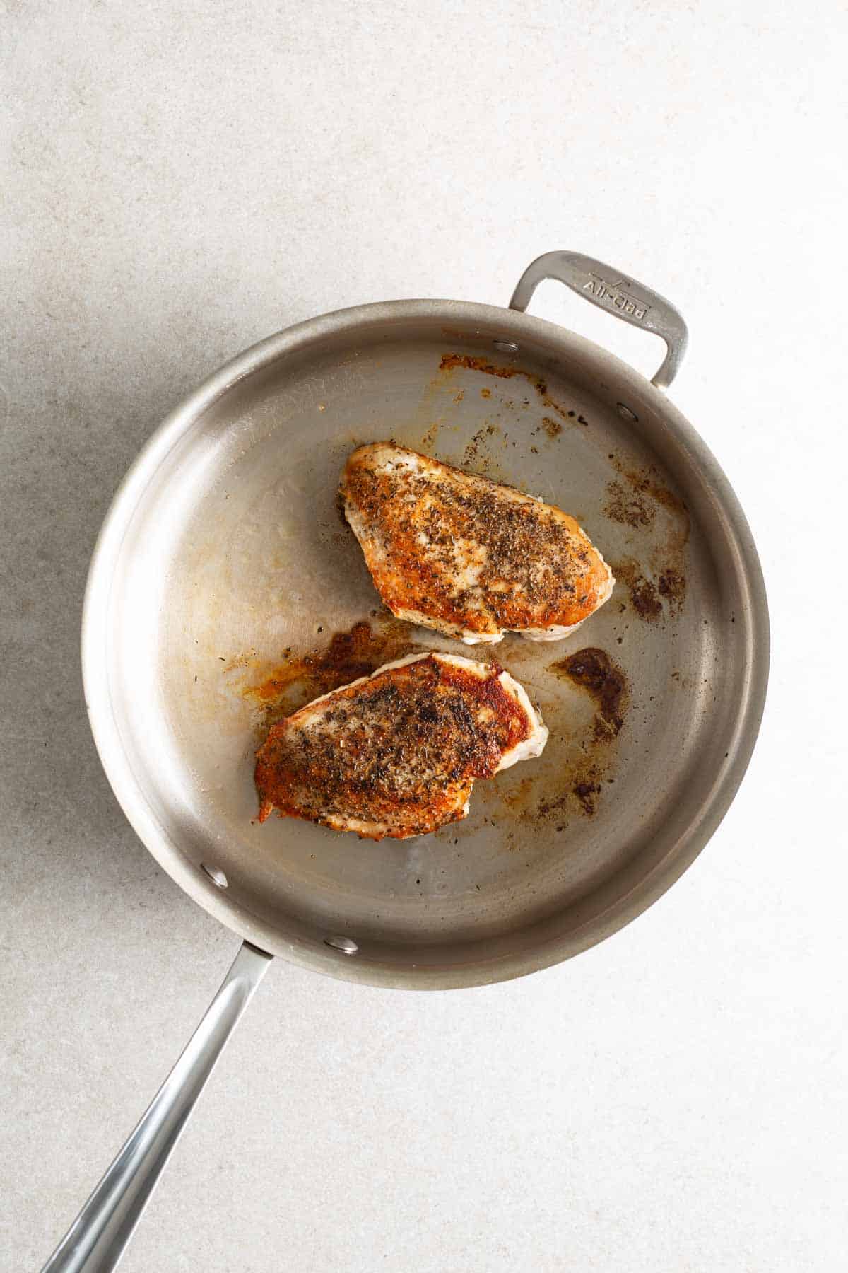 A pan with two pieces of chicken in it.