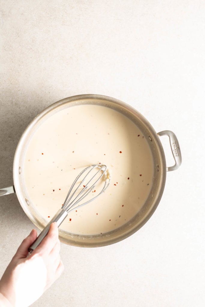 A person holding a whisk in a pan.