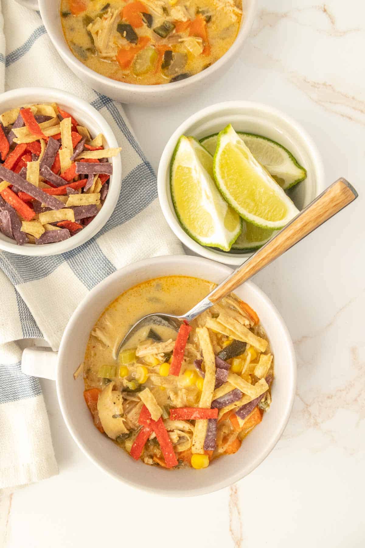 Three bowls of chicken enchilada soup on a table.