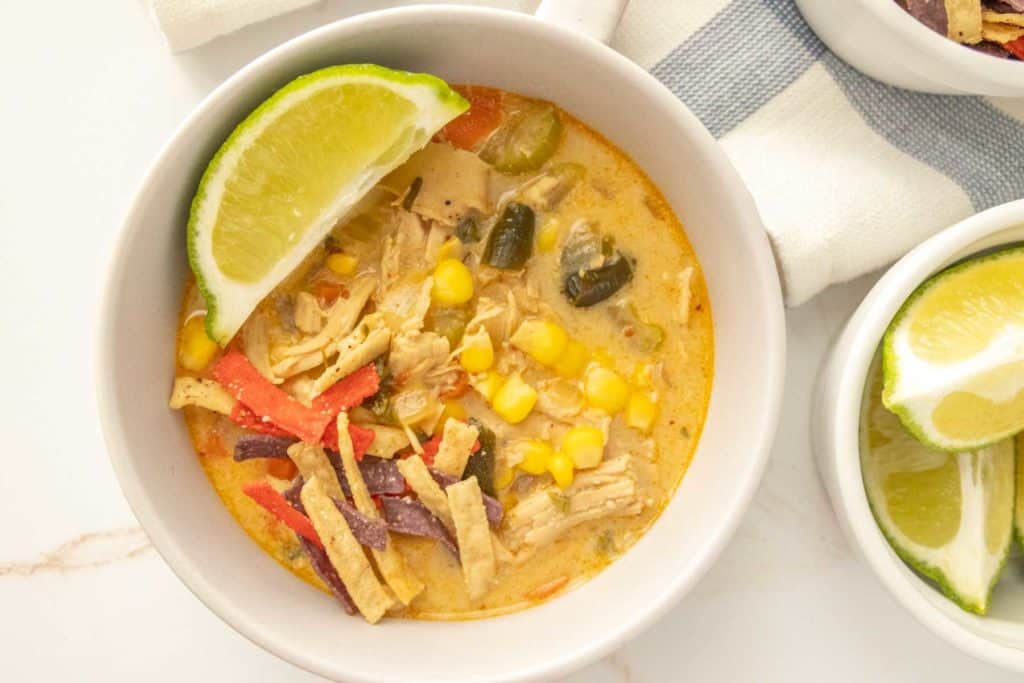 Two bowls of chicken poblano soup with lime wedges.