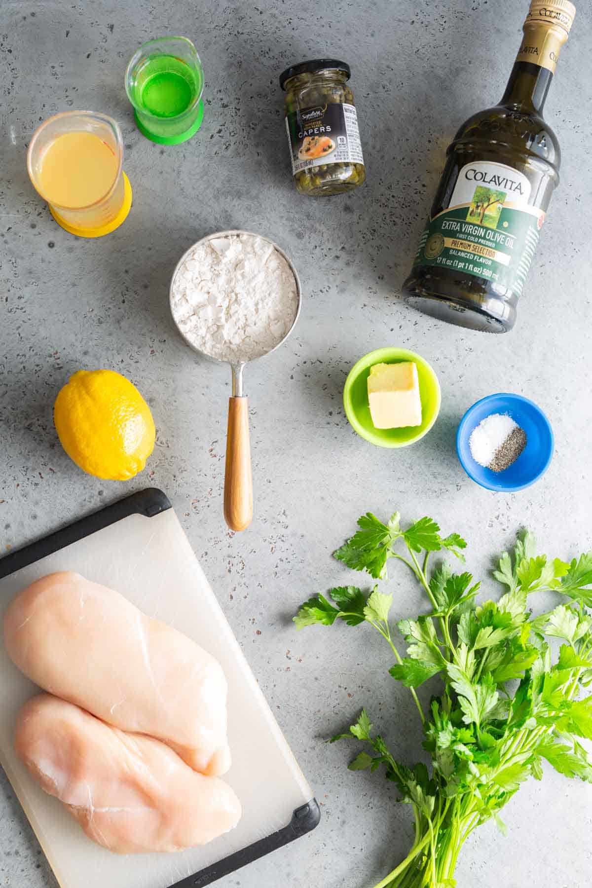 The ingredients for chicken scallopini on a cutting board.