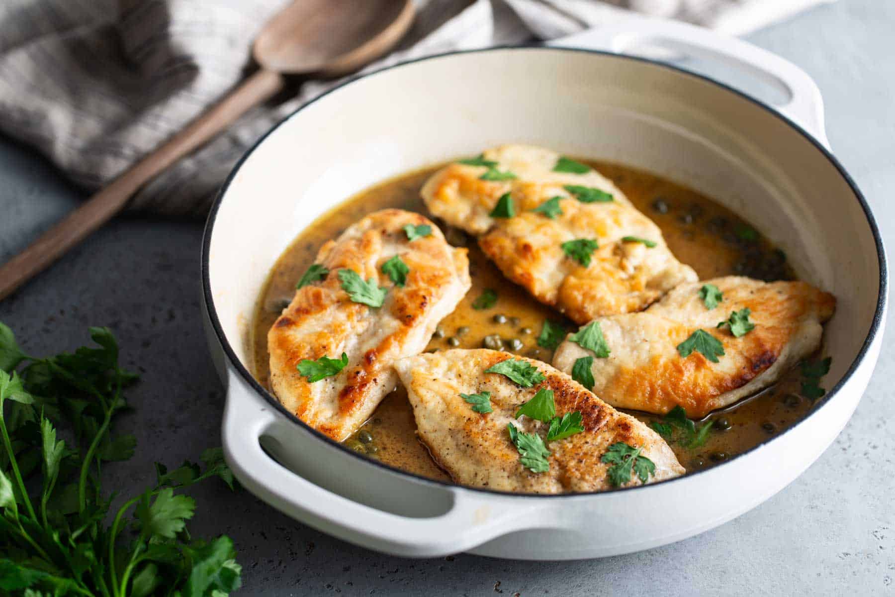 Chicken breasts in a white dish with parsley.