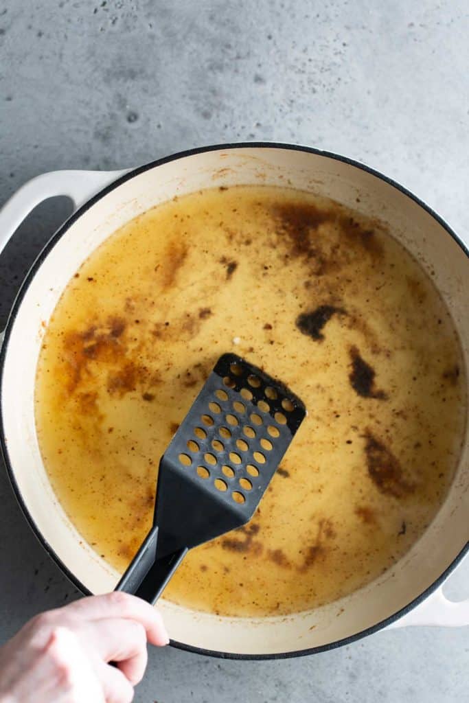 A person using a spatula to stir a pot of sauce.