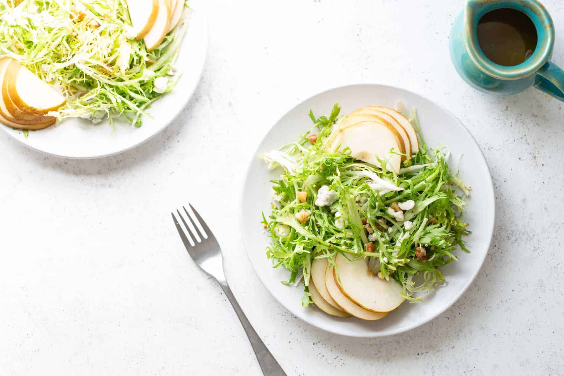 A plate of frisee salad with pears and walnuts.