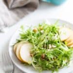 A plate of frisee salad with pears and walnuts.