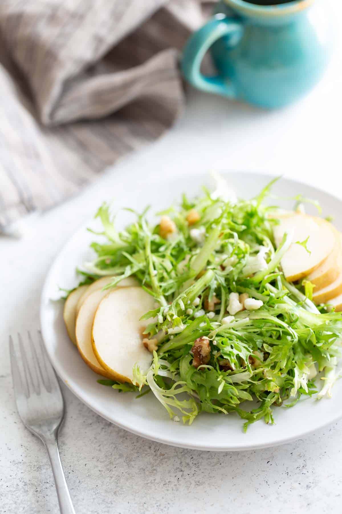 A plate of frisee salad with pears and walnuts.