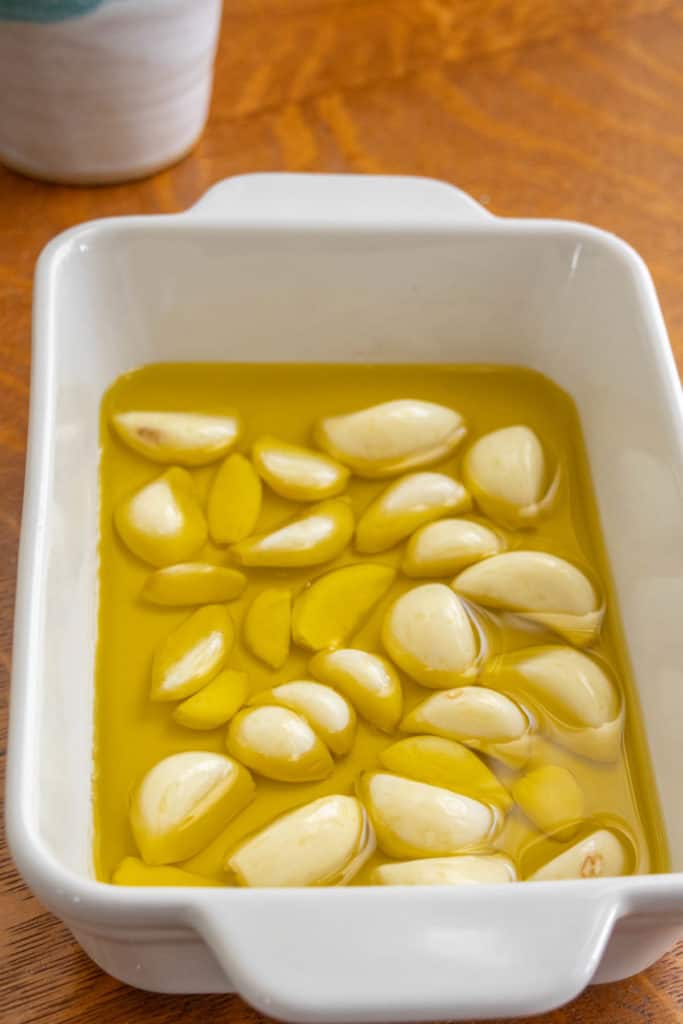 A white baking dish with garlic in it.