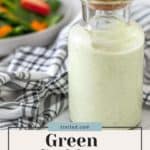 Bottle of green goddess dressing next to a chicken broccoli pasta salad and a checkered napkin.