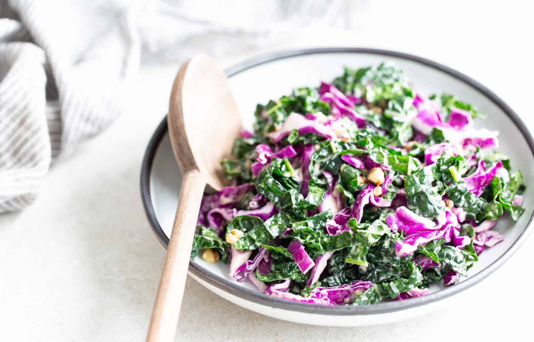 Kale slaw in a bowl with a wooden spoon.