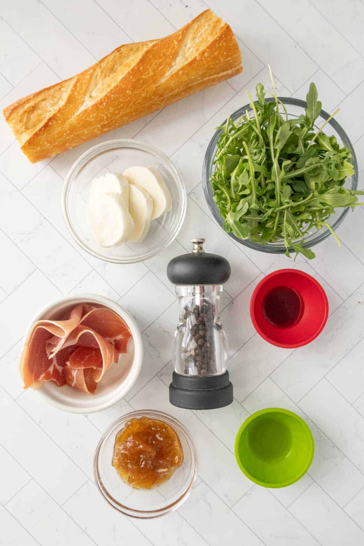 The ingredients for a sandwich are laid out on a white countertop.