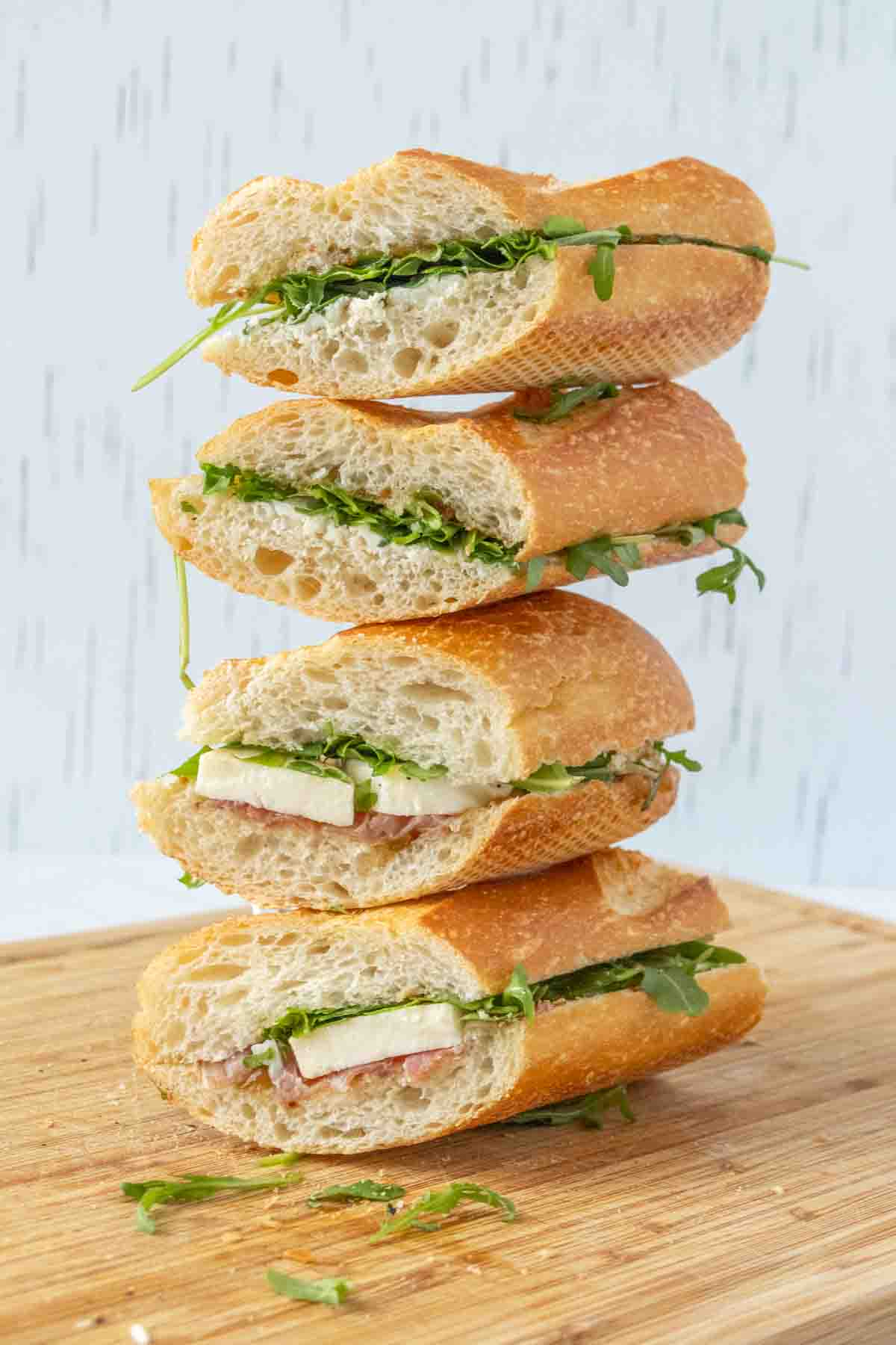 A stack of sandwiches on a wooden cutting board.