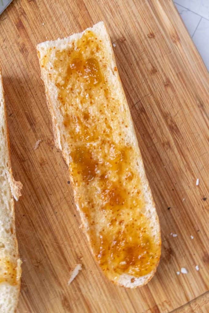 Two slices of bread with fig jam on a cutting board.