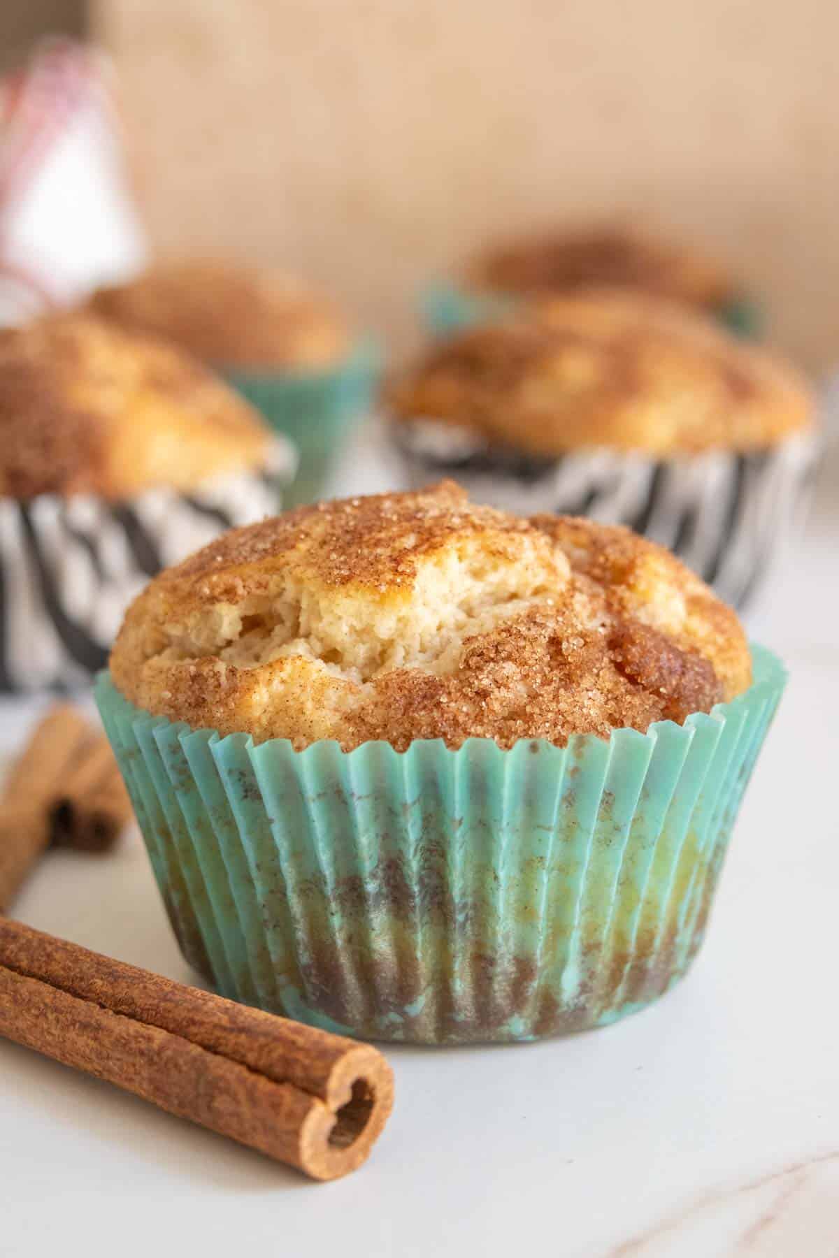 Cinnamon muffins with cinnamon sticks on a white table.