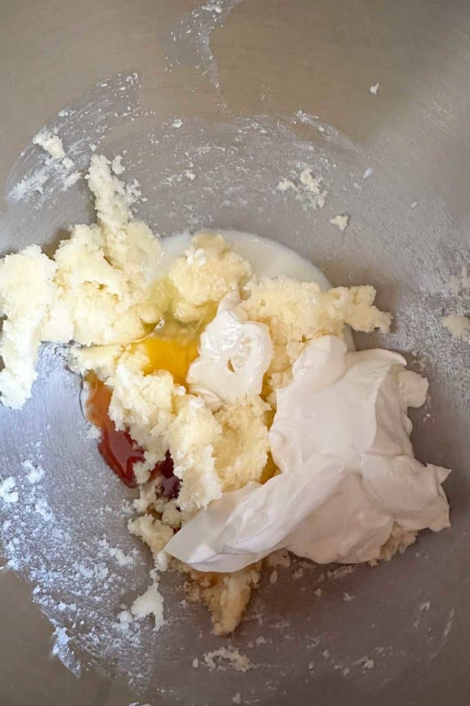 A mixing bowl with eggs, sugar and sour cream.
