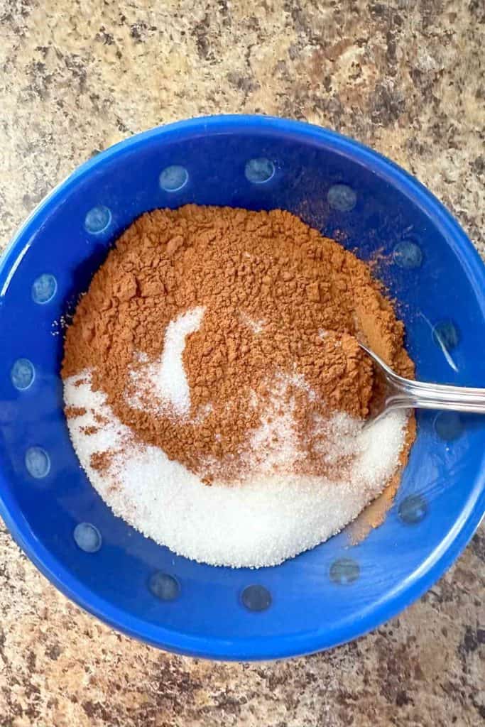 A blue bowl filled with sugar and cinnamon.