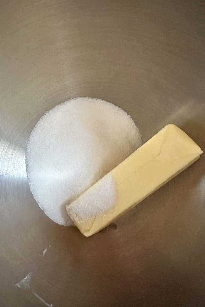 Butter and sugar in a metal mixing bowl.