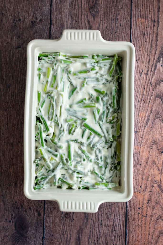 A ceramic dish containing a raw, asparagus casserole before baking.