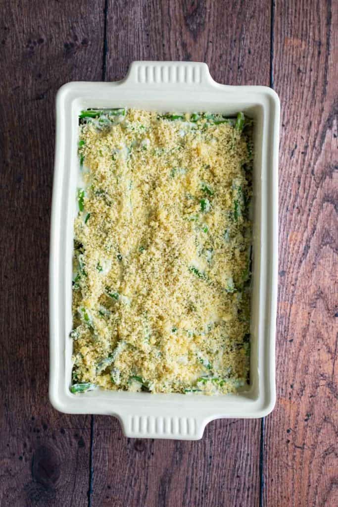 A casserole dish filled with a breadcrumb-topped baked dish on a wooden table.