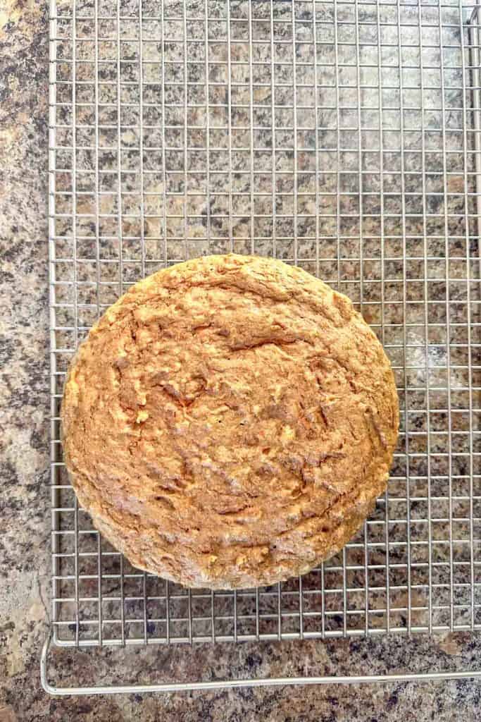 A freshly baked round loaf of bread cooling on a wire rack.