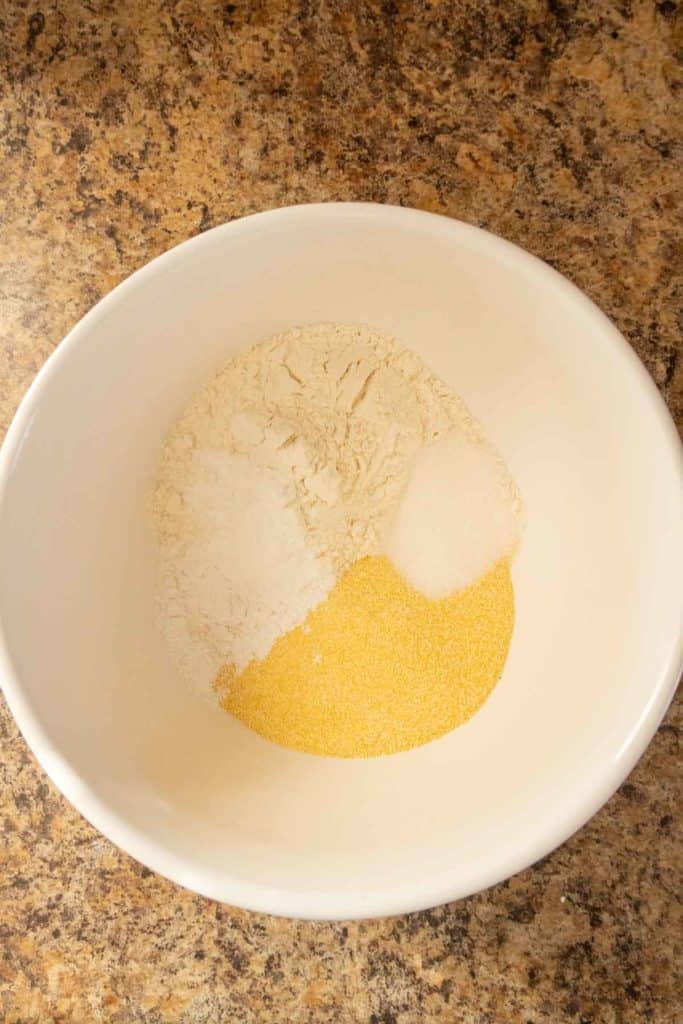 Bowl containing separate portions of white flour and yellow cornmeal.