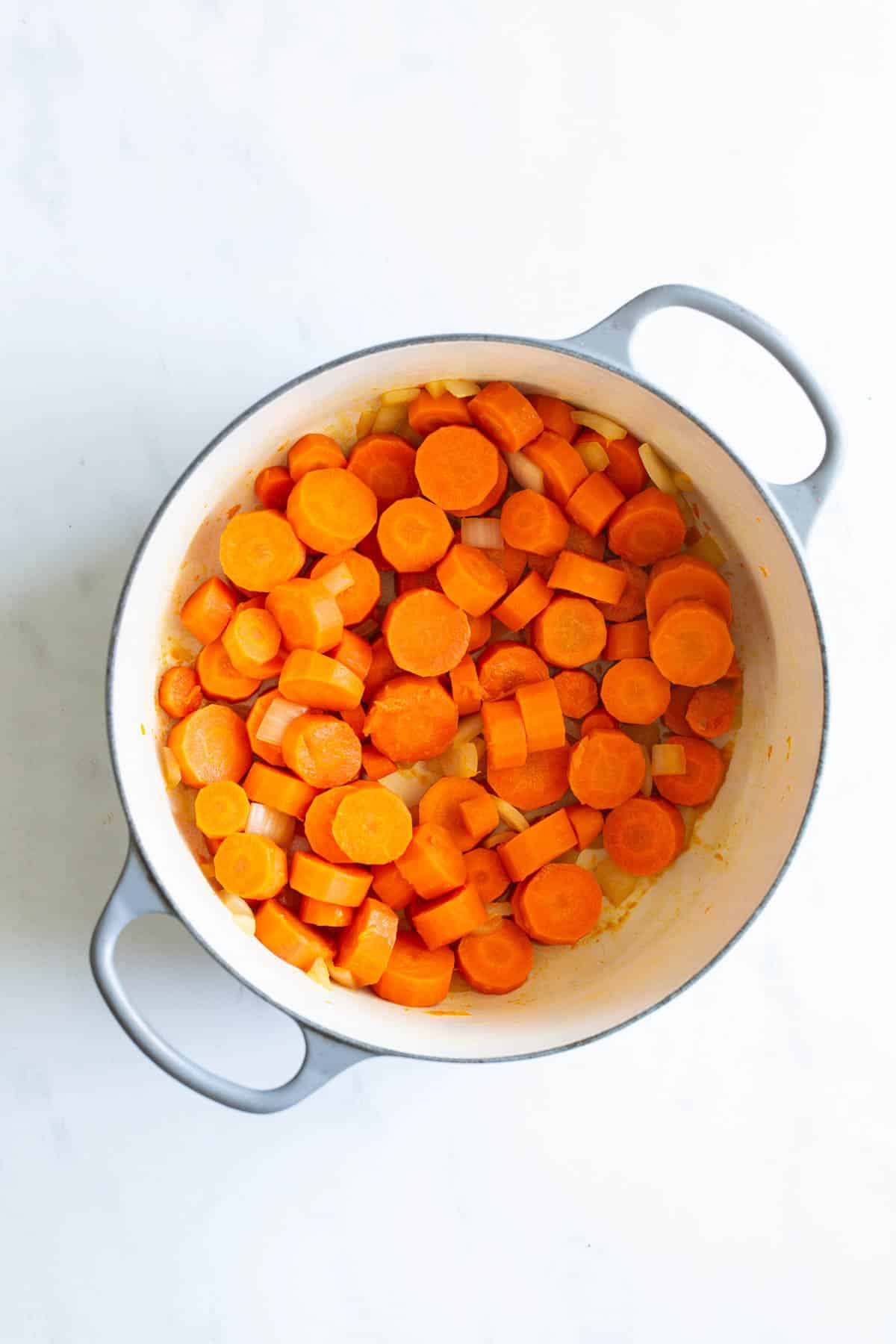 Sliced carrots in a white cooking pot.