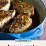 Four seared pork chops with a rich honey garlic glaze in a blue skillet, garnished with chopped herbs. Text at the bottom reads "honey garlic pork chops.