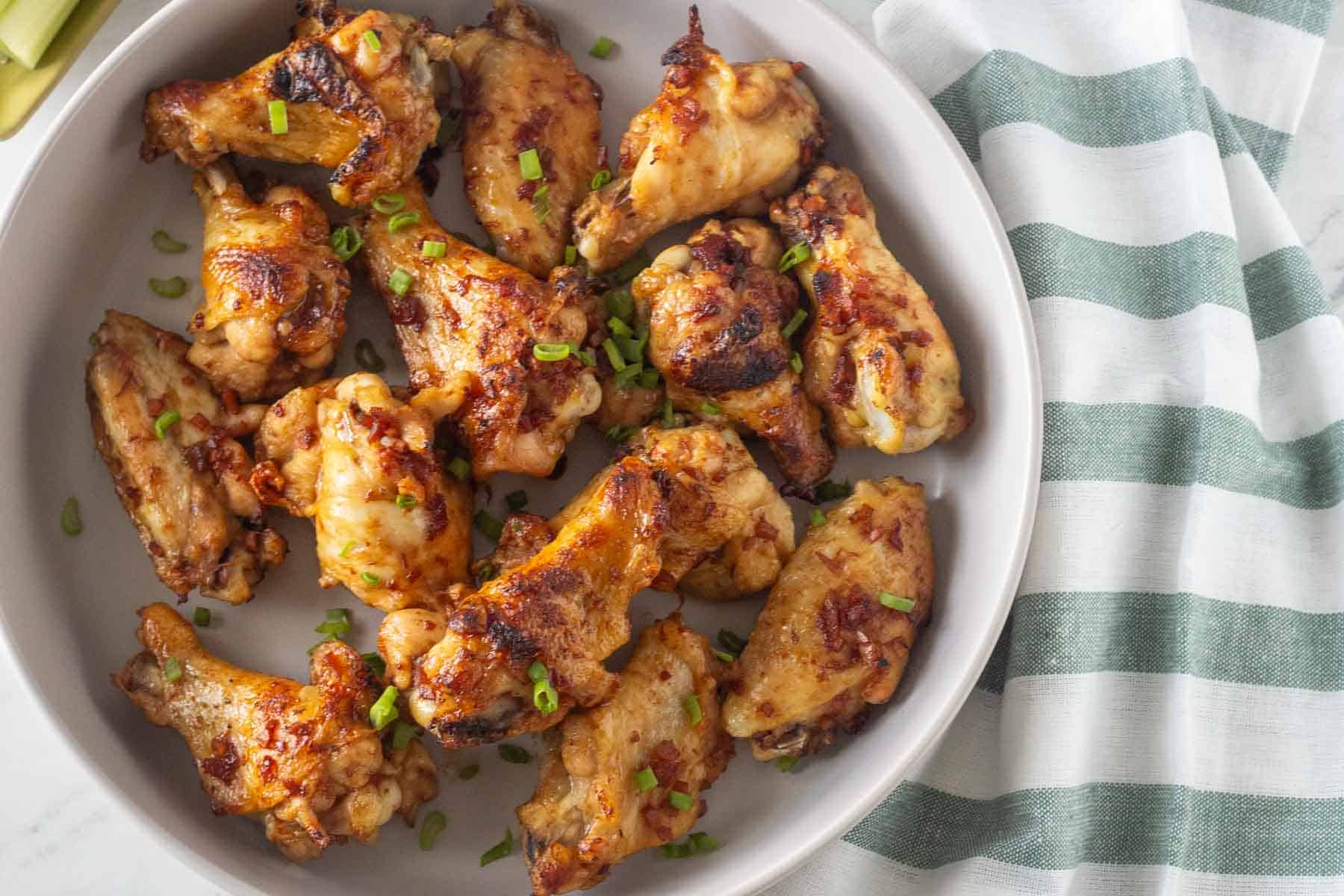 A plate of chicken wings garnished with chopped green onions.