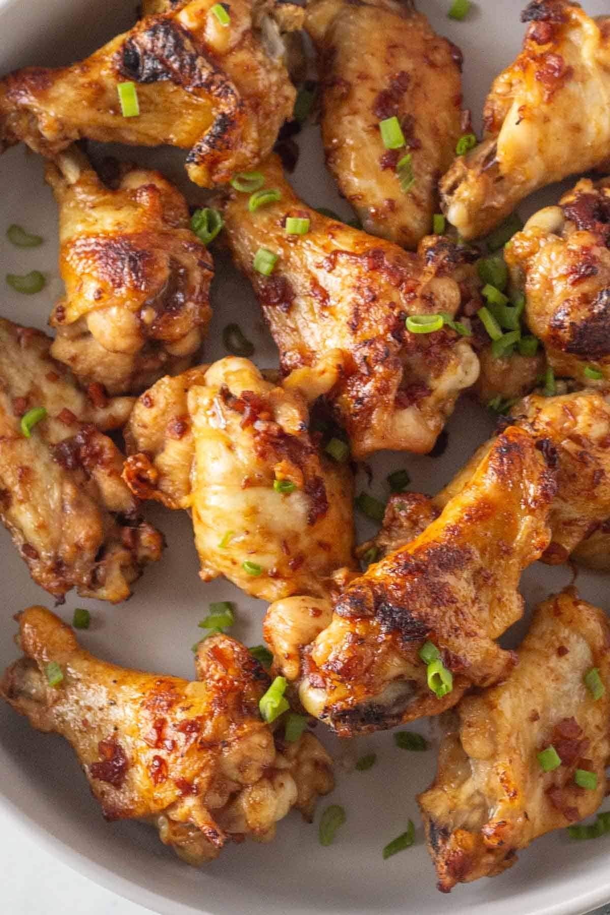 A plate of chicken wings garnished with chopped green onions.