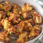 A bowl of roasted chicken wings garnished with green onions.