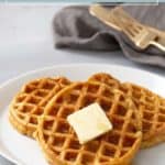 Three sweet potato waffles topped with a pat of butter and syrup on a white plate, with a fork and knife in the background—perfectly warm, fluffy sweet potato waffles for breakfast or brunch.