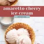 Two wooden bowls filled with scoops of cherry ice cream, one cherry visible, rest on a white tiled surface. Text overlay reads "amaretto cherry ice cream.