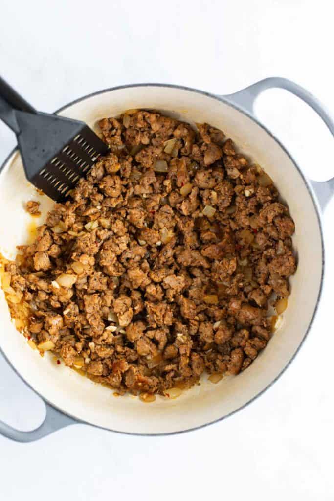 Cooked ground meat with onions in a white pot, with a black spatula.