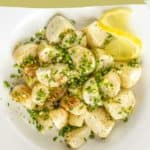 A plate of roasted turnips is garnished with chopped chives and served with lemon wedges. Text on the image reads "roasted turnips with chives and lemon.