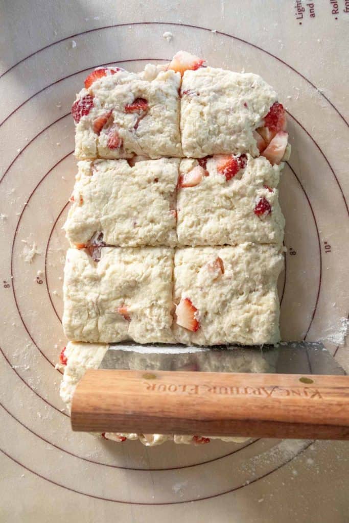 Freshly cut strawberry biscuit dough on a floured mat.