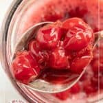 A spoon holding cherry compote hovers above a jar brimming with more cherry compote; text reads "Sour Cherry Compote.