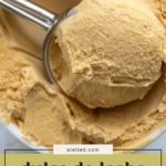 A metal ice cream scoop serves creamy dulce de leche ice cream from a container. The text on the image highlights “dulce de leche ice cream.”.
