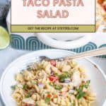 A plate of taco pasta salad with fresh vegetables and herbs sits in front of a casserole dish; a fork rests on the plate, ready to enjoy this flavorful taco pasta salad.