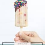 A hand holds a banana split popsicle dipped in chocolate and topped with rainbow sprinkles—banana popsicles reimagined. Text at the bottom reads "banana split popsicles.
