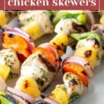 Chicken skewers grilled to perfection with pineapple, red onion, green bell pepper, and red bell pepper are served on a plate.