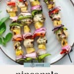 A plate with four chicken skewers featuring juicy chunks of chicken, pineapple, red onion, and red and green bell peppers. Text below reads "pineapple chicken skewers.