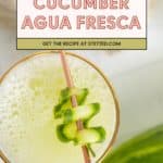 A glass of cucumber agua fresca with a copper straw, garnished with a cucumber ribbon and placed beside a fresh cucumber. Text overlay: "Cucumber Agua Fresca. Get the refreshing recipe at stetted.com.